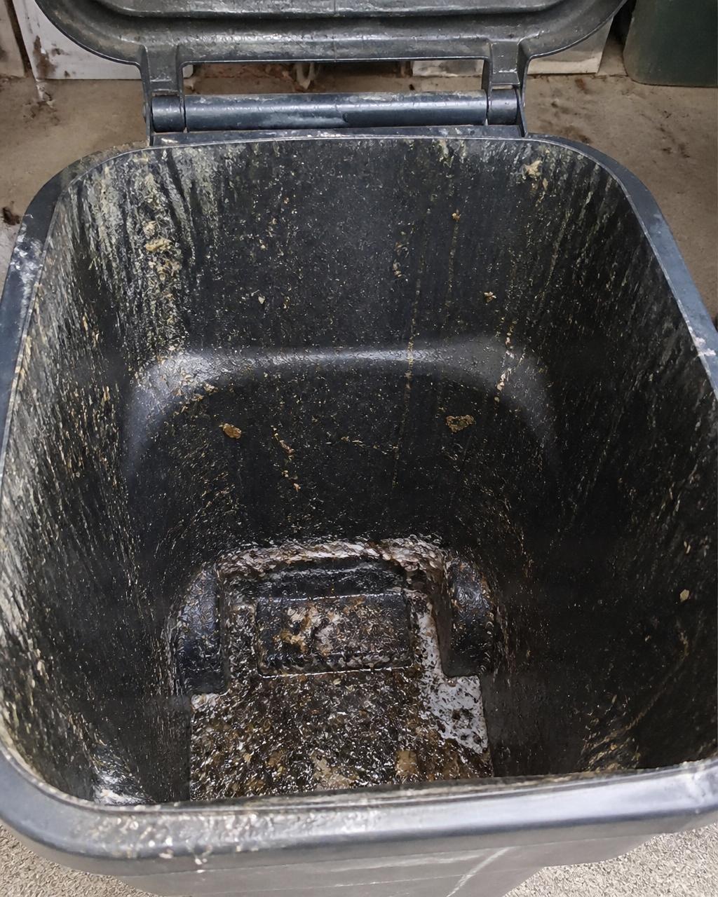 Inside of a filthy trash can caked with grime before cleaning